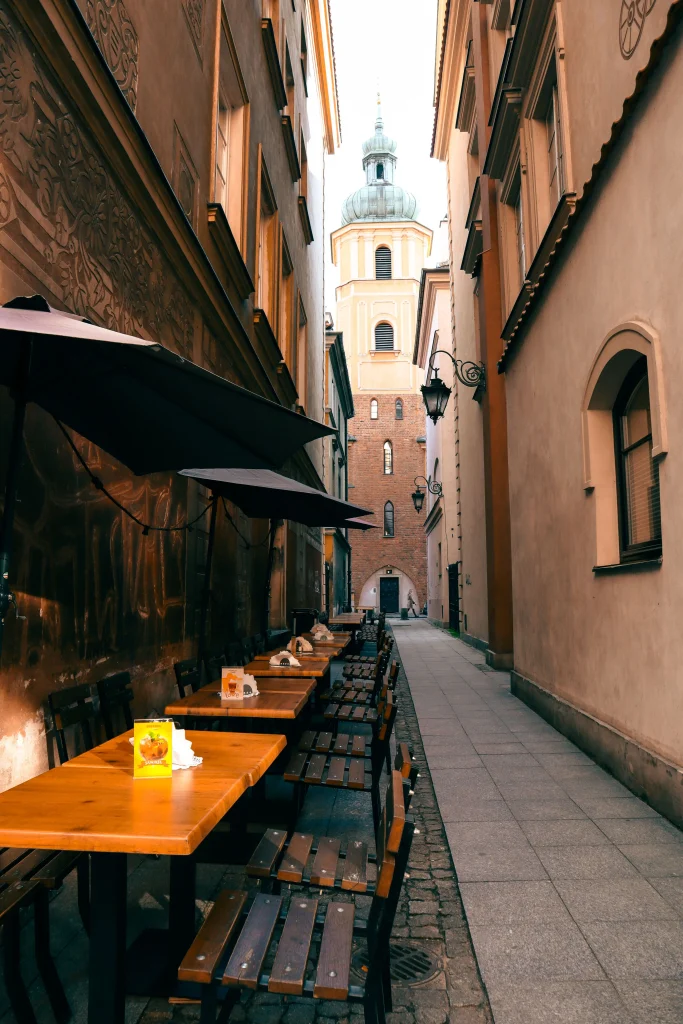 Prague vs Krakow: Which Is Cheaper for Backpackers in 2026? 2 Outdoor café terrace with umbrellas in a narrow historic European street