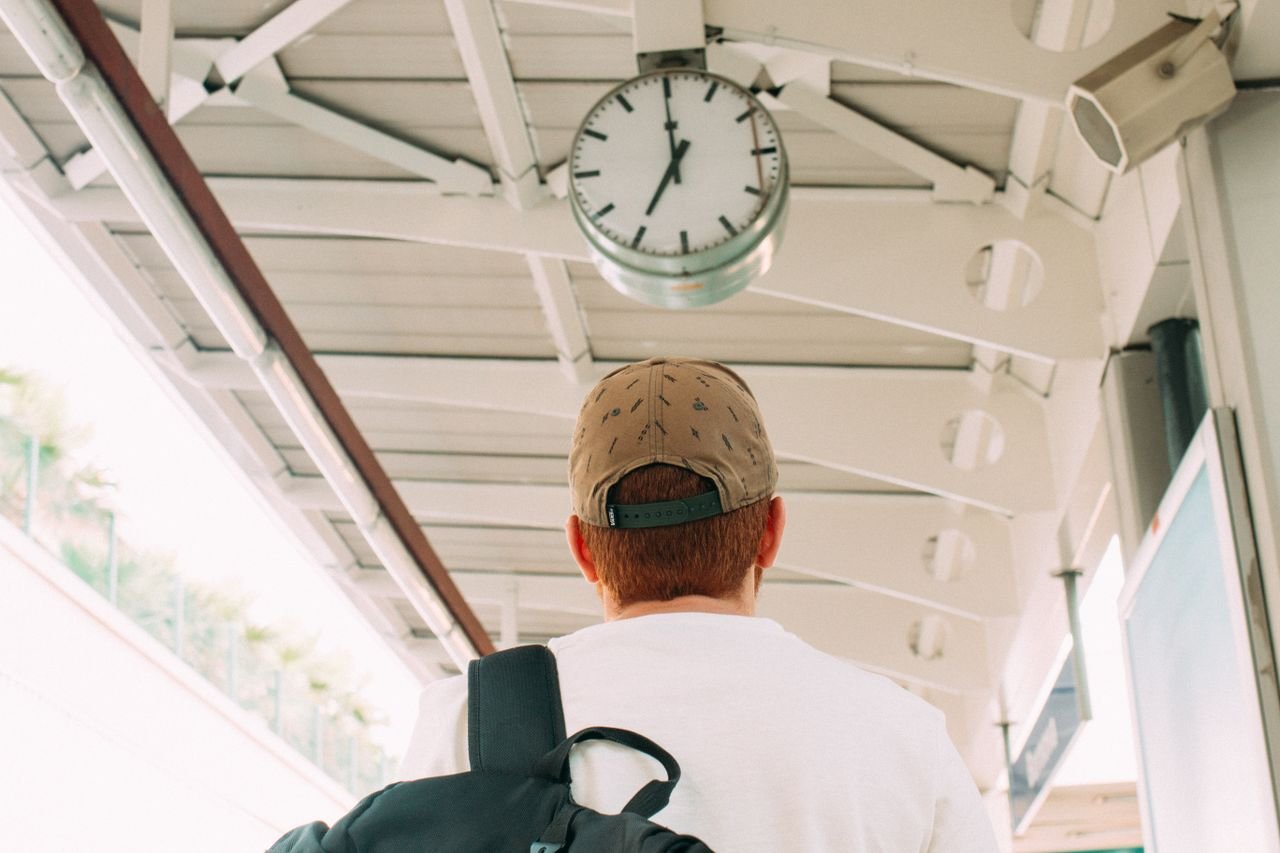 Traveler at a train station platform looking at the clock, anticipating departure.