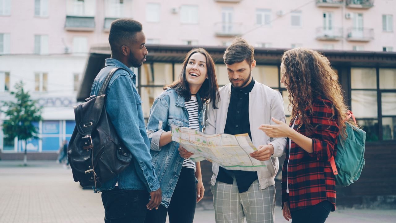 Four young friends reading a map outdoors, planning their city adventure.